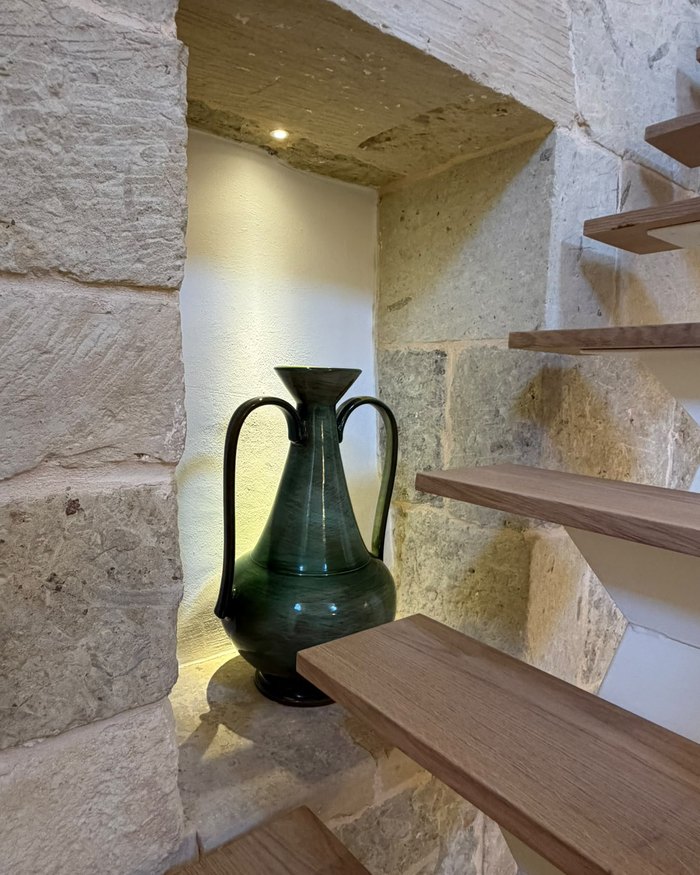 L'anfora in ceramica verde nella nicchia, accanto ai gradini in legno