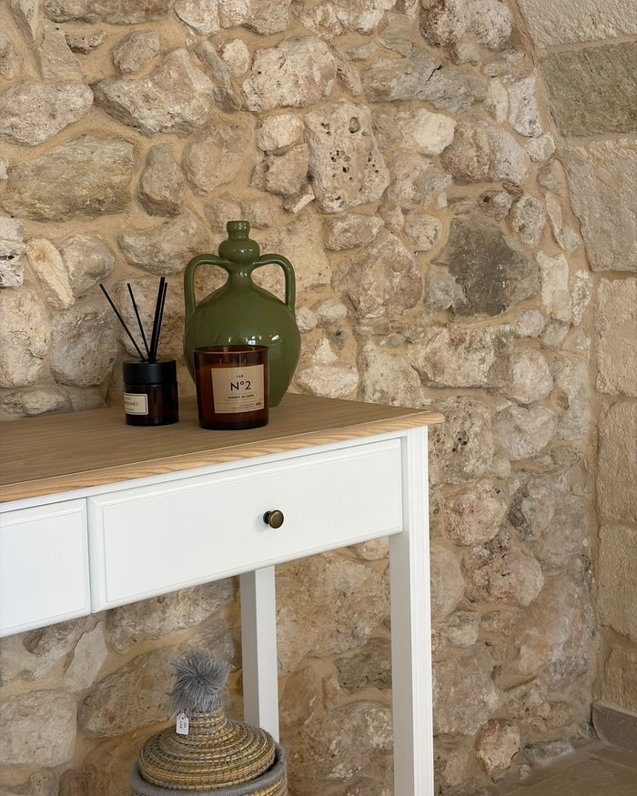 La consolle con la ceramica verde, contro il muro in pietra dell'appartamento Malìa