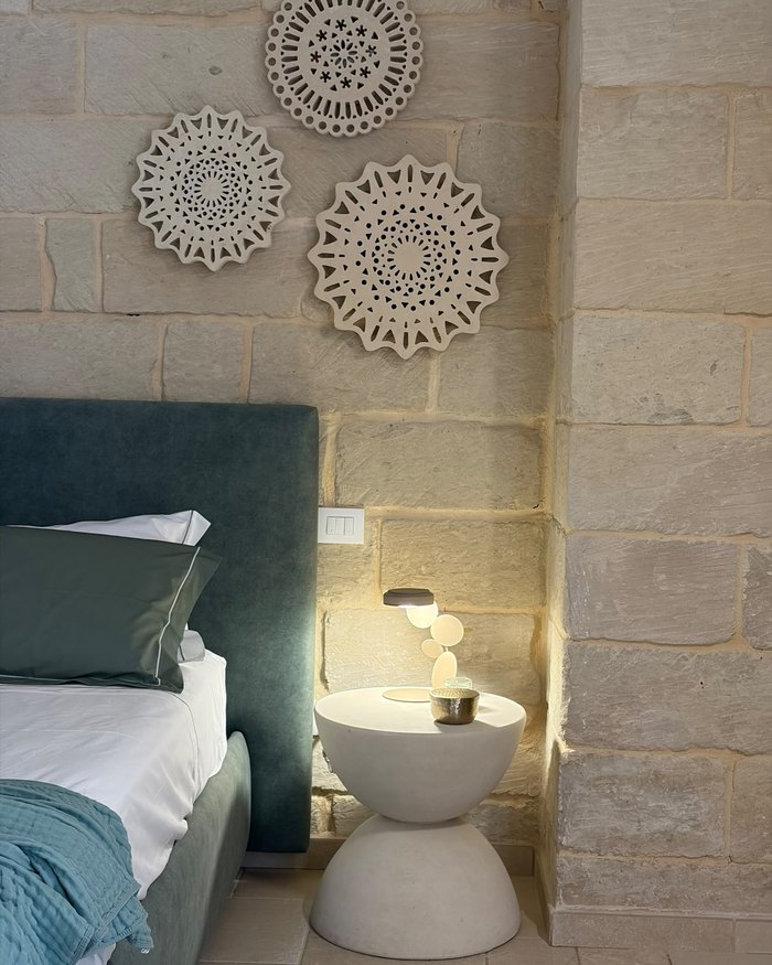Il comodino e i rosoni in ceramica sopra il letto, nell'appartamento Malìa