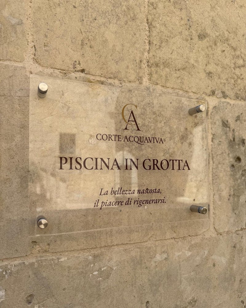 L'insegna della piscina in grotta di Corte Acquaviva, incisa sul vetro